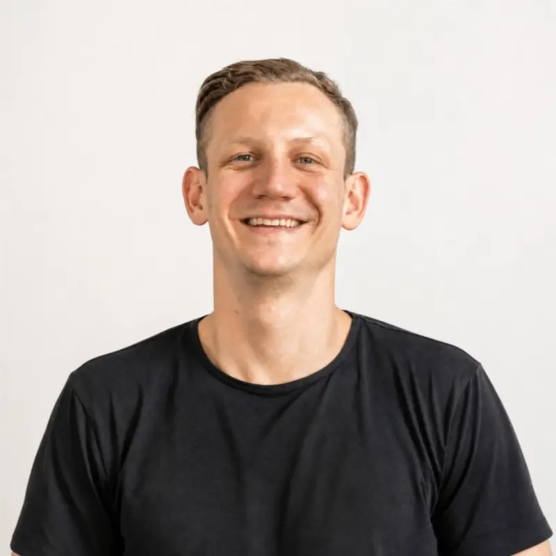 John Peslar, founder of LaunchpadFast, smiling in a black T-shirt against a plain light wall